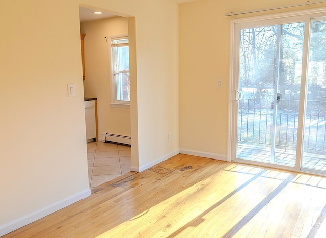 spare room featuring baseboard heating and light hardwood / wood-style flooring