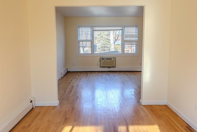 spare room featuring light wood-type flooring, an AC wall unit, and a baseboard radiator