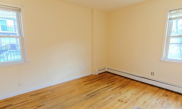 spare room featuring baseboard heating and light hardwood / wood-style floors