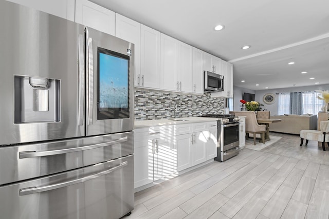 kitchen featuring stainless steel appliances, white cabinetry, sink, and backsplash