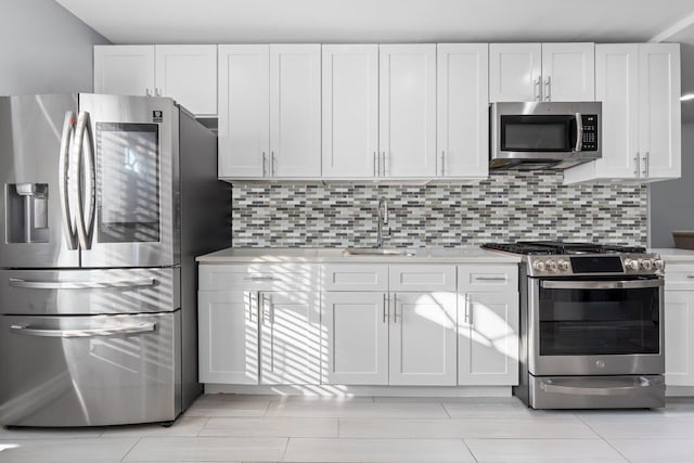 kitchen with stainless steel appliances, white cabinets, sink, and tasteful backsplash