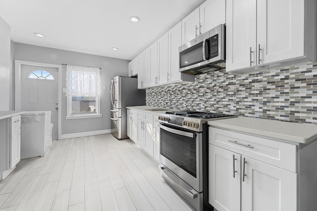 kitchen featuring stainless steel appliances, white cabinets, sink, and backsplash