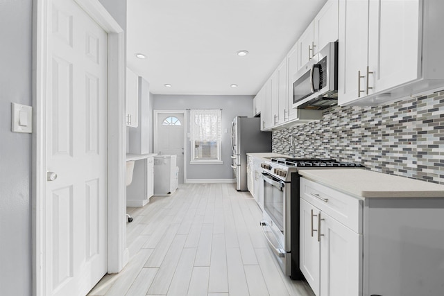 kitchen featuring appliances with stainless steel finishes, light hardwood / wood-style floors, white cabinets, and tasteful backsplash