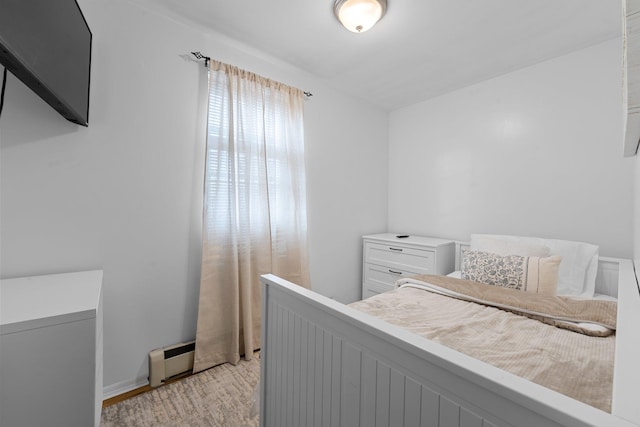 bedroom featuring a baseboard heating unit and light wood-type flooring