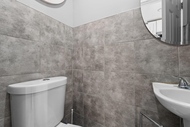 bathroom featuring sink, tile walls, and toilet