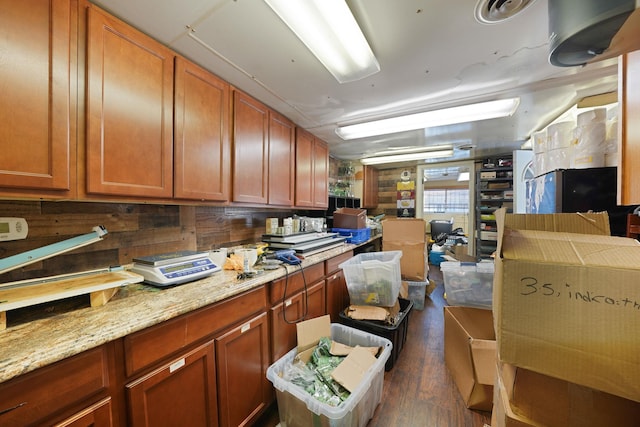 kitchen featuring dark hardwood / wood-style flooring, wooden walls, and light stone countertops