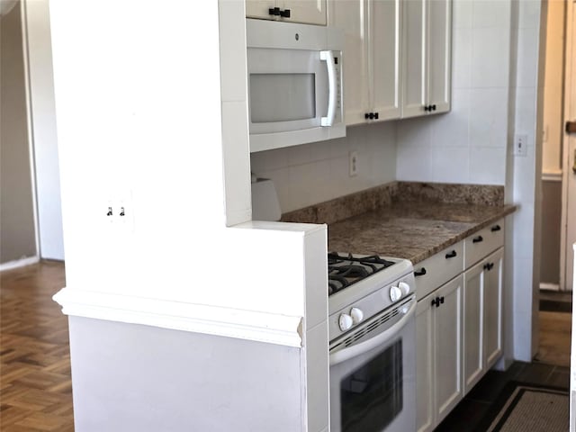 kitchen featuring white appliances, white cabinetry, dark parquet flooring, and dark stone countertops