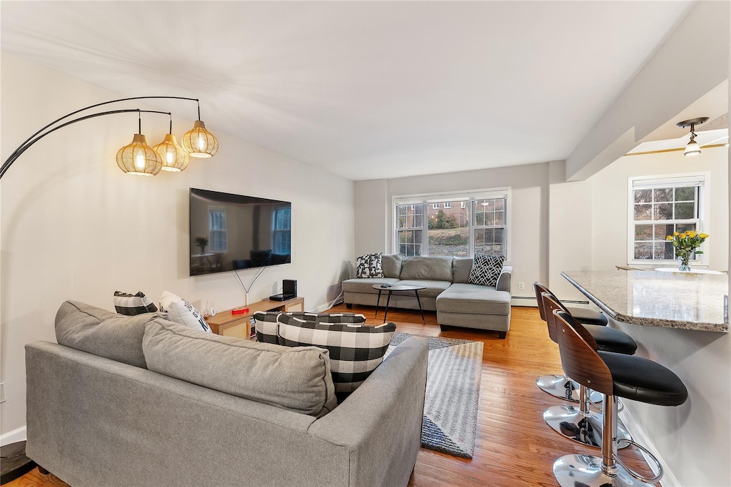 living room featuring a baseboard heating unit, light hardwood / wood-style floors, and a notable chandelier