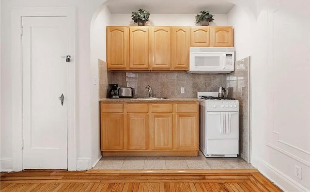 kitchen featuring sink, light brown cabinets, white appliances, and tasteful backsplash