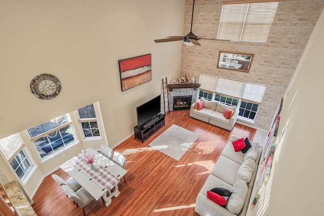 living room featuring a towering ceiling, a fireplace, and hardwood / wood-style floors