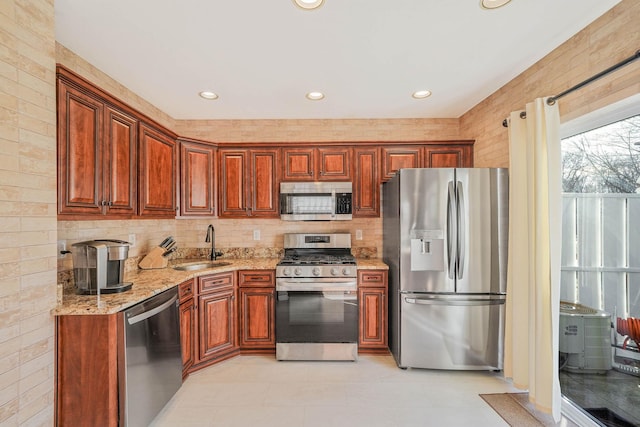 kitchen featuring light stone counters, stainless steel appliances, and sink