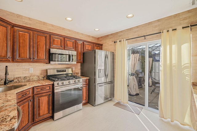 kitchen featuring sink, stainless steel appliances, and light stone counters