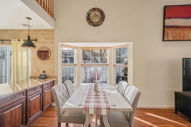 dining space featuring a high ceiling and hardwood / wood-style flooring