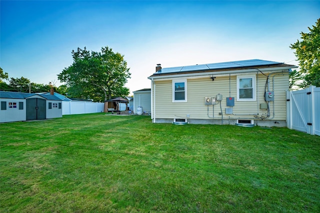 back of house with a lawn, a gazebo, a shed, and solar panels