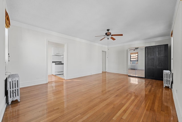 unfurnished living room featuring hardwood / wood-style floors, crown molding, and radiator