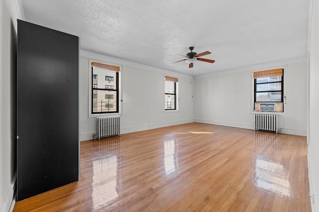 empty room featuring ceiling fan, light wood-type flooring, ornamental molding, and radiator