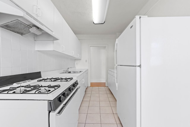 kitchen with sink, light tile patterned floors, a textured ceiling, white appliances, and white cabinets