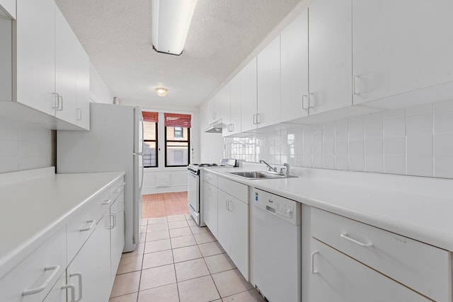 kitchen with white cabinetry, light tile patterned flooring, white appliances, and sink