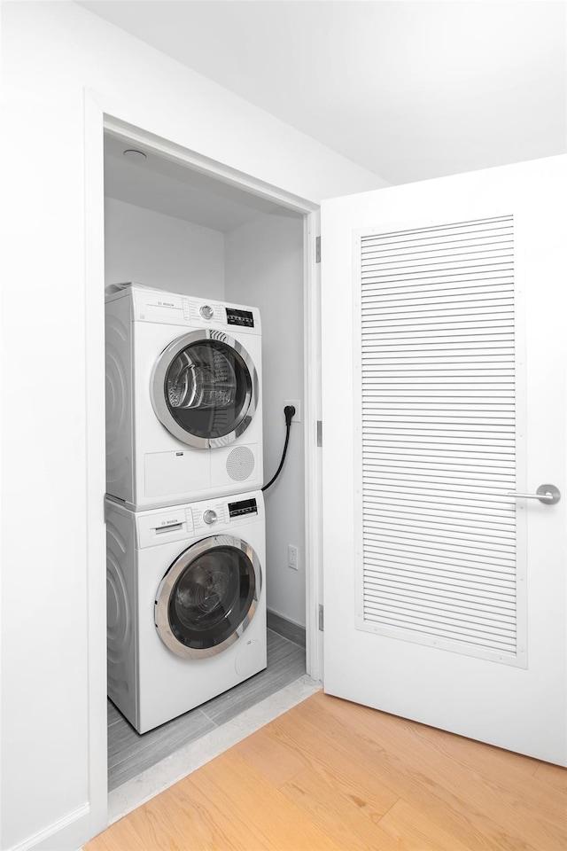 laundry area featuring stacked washer and dryer and hardwood / wood-style flooring