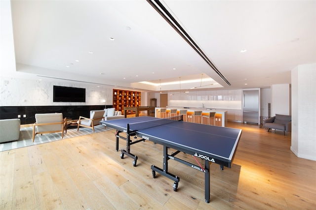 playroom featuring light wood-type flooring and a raised ceiling