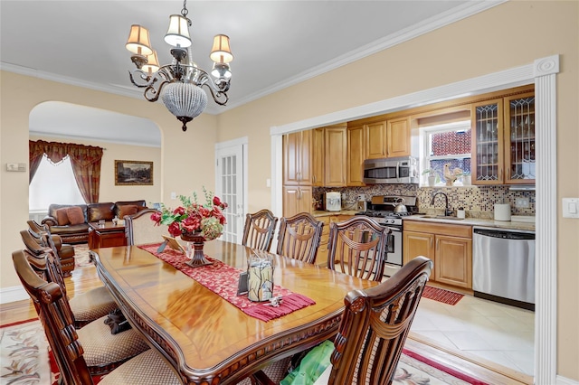 dining area featuring light tile patterned flooring, sink, crown molding, and an inviting chandelier