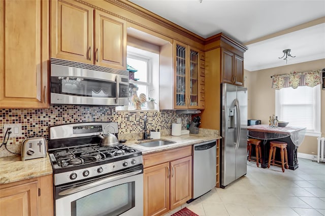 kitchen featuring decorative backsplash, stainless steel appliances, light stone counters, and sink