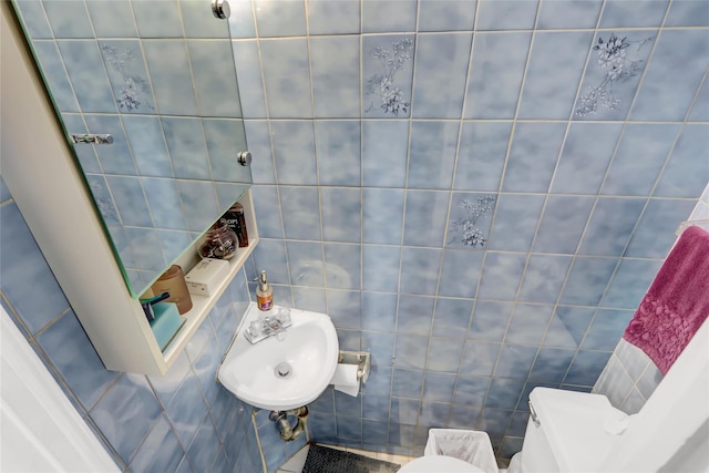 bathroom with sink, tile walls, and toilet