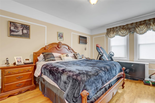 bedroom with light hardwood / wood-style flooring and a wall mounted air conditioner