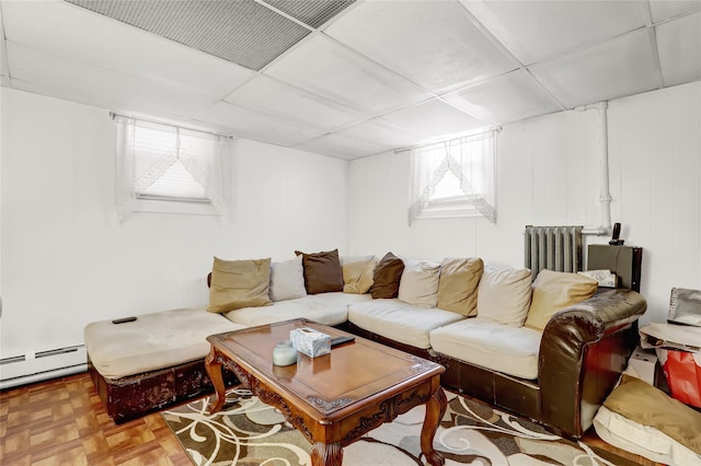 living room with radiator, a paneled ceiling, a baseboard heating unit, and parquet flooring