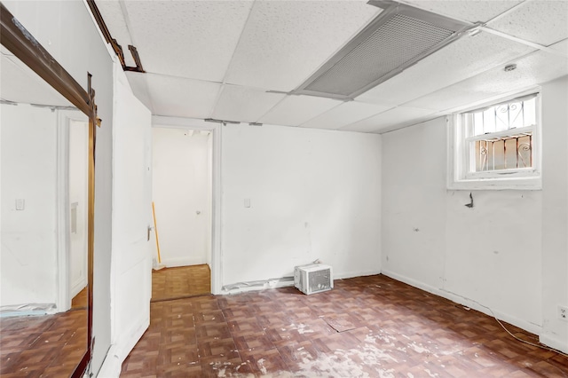 basement featuring parquet floors and a drop ceiling