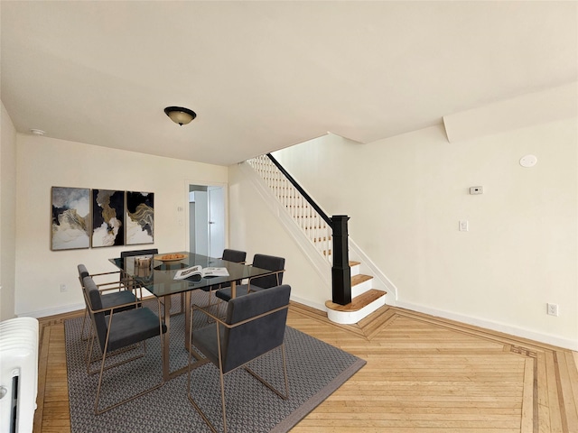 dining room featuring stairway, radiator, wood finished floors, and baseboards