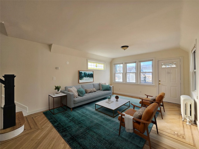 living room with vaulted ceiling, radiator heating unit, baseboards, and light wood-type flooring