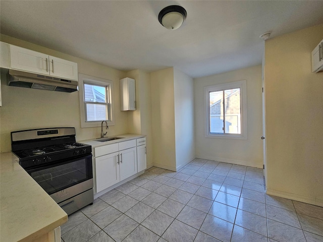 kitchen featuring light countertops, stainless steel range with gas stovetop, under cabinet range hood, and a sink