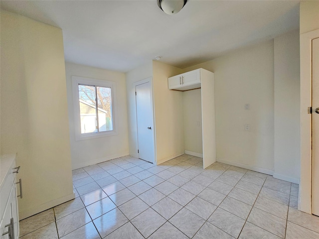 unfurnished bedroom with light tile patterned floors, a closet, and baseboards