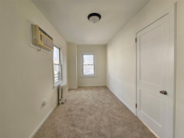 carpeted spare room featuring radiator, baseboards, and a wall mounted air conditioner