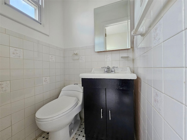 half bath featuring vanity, tile walls, and toilet