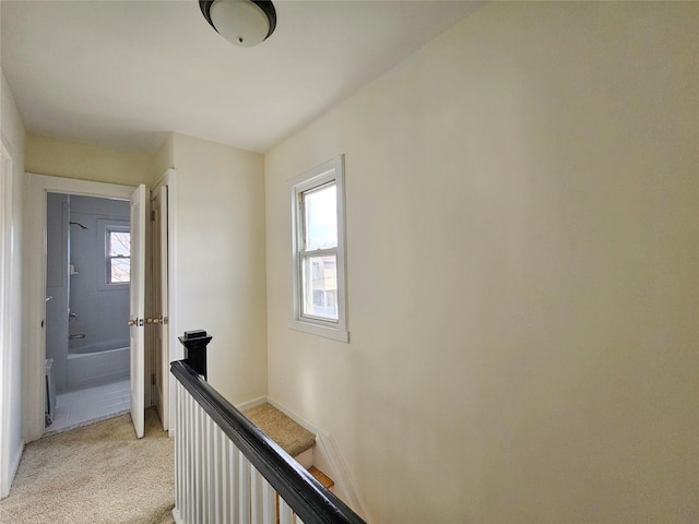 corridor with an upstairs landing, light colored carpet, and baseboards