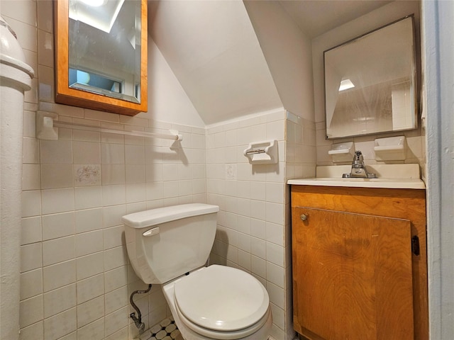 bathroom featuring toilet, tile walls, vanity, and vaulted ceiling