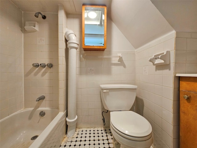 bathroom featuring tile patterned floors, toilet, shower / bathing tub combination, tile walls, and vanity