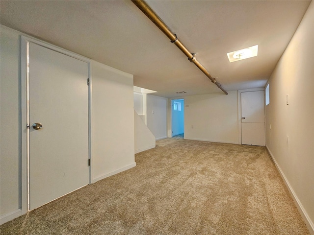 finished basement featuring light colored carpet and baseboards