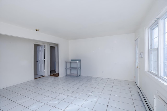 spare room with light tile patterned flooring, a baseboard heating unit, and plenty of natural light