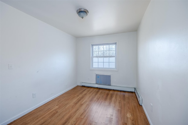 spare room featuring light wood-type flooring and a baseboard heating unit