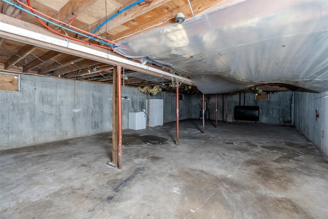 basement with white refrigerator and washer / dryer