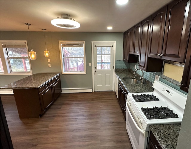 kitchen featuring white gas stove, pendant lighting, dark brown cabinets, and sink