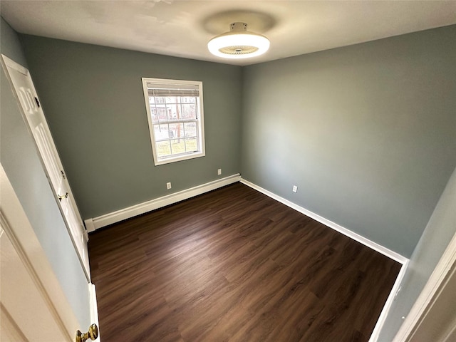 unfurnished bedroom with a baseboard heating unit and dark wood-type flooring