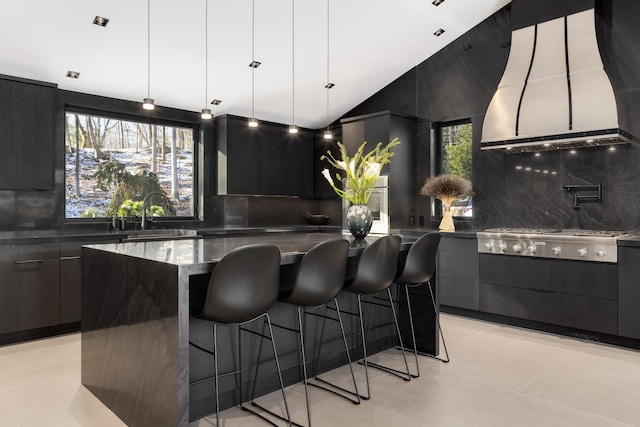 kitchen featuring sink, lofted ceiling, tasteful backsplash, a spacious island, and stainless steel gas stovetop