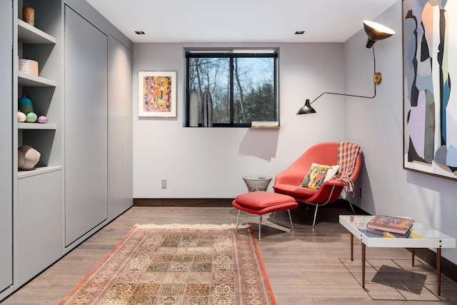 sitting room featuring built in shelves and hardwood / wood-style floors