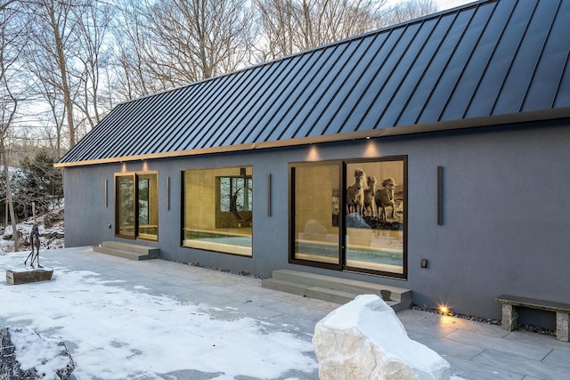 snow covered house featuring a patio area