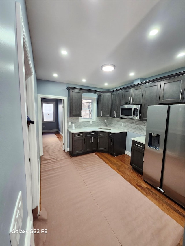 kitchen featuring backsplash, sink, light hardwood / wood-style flooring, and appliances with stainless steel finishes