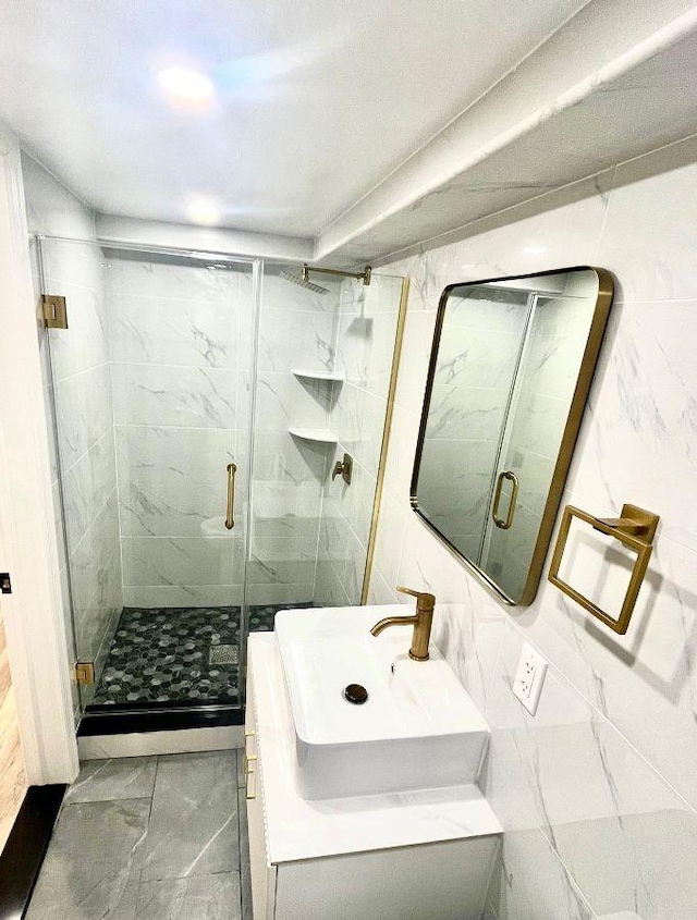 bathroom with vanity, walk in shower, and tile walls